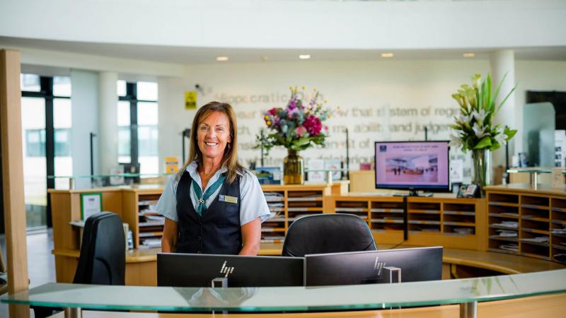 Receptionist standing behind her desk and smiling