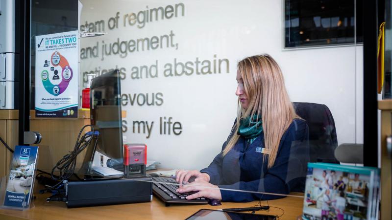 Admissions worker sitting behind a desk and working on her computer