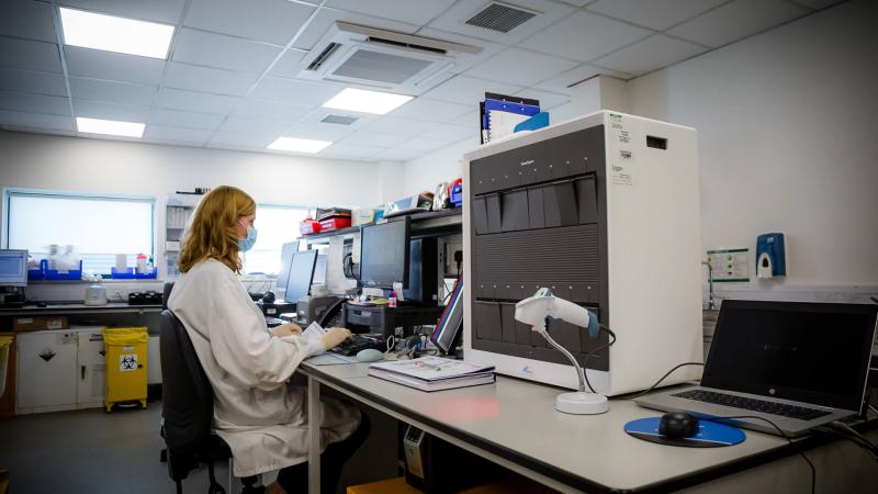 Clinical Laboratory Technician sitting at a desk and looking at results of a test on her computer screen
