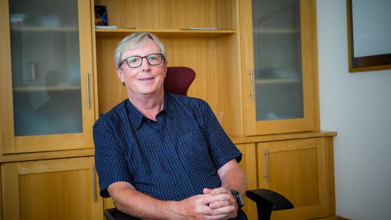 A consultant sitting with his legs crossed and smiling in his office