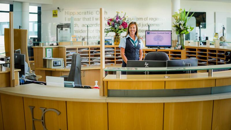 Receptionist standing behind her desk and smiling