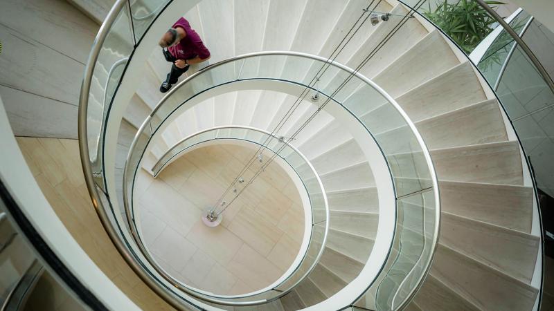Looking down a spiral staircase with a worker walking down them.