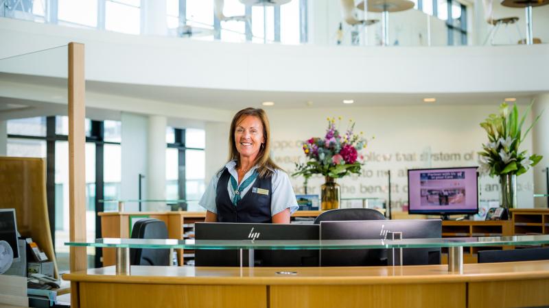 Receptionist standing behind her desk and smiling