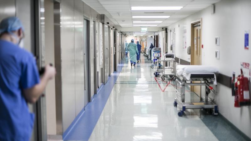 Nurses and Doctors walking up and down a corridor wearing PPE.