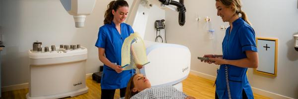 two nurses standing beside a patient getting Cyberknife treatment 